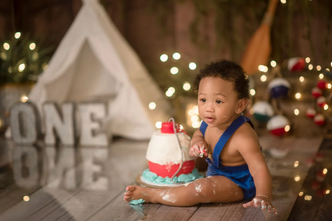 Birthday boy looking at the camera beside his smashed cake