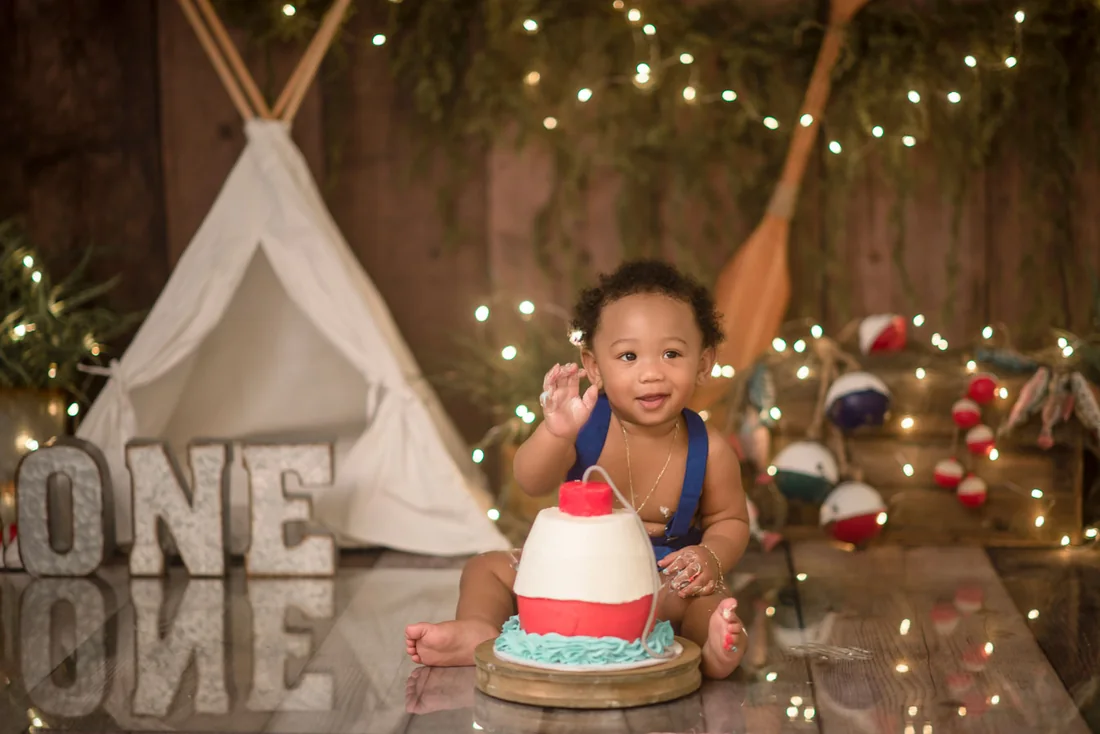 Birthday boy reaching into a red and white cake
