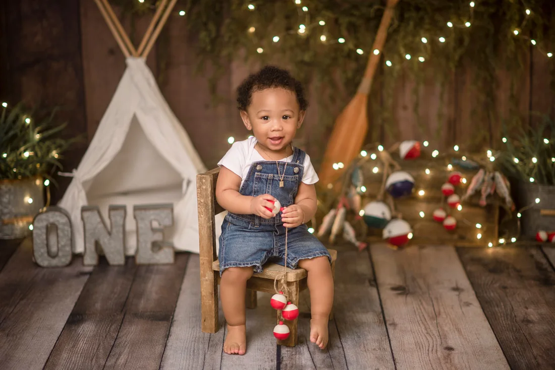 Birthday boy sitting on a wooden chair with fishing-themed decorations