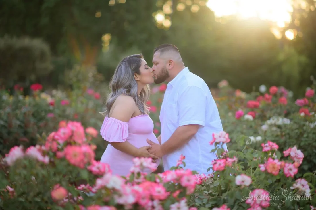 Expectant parents together in a rose garden
