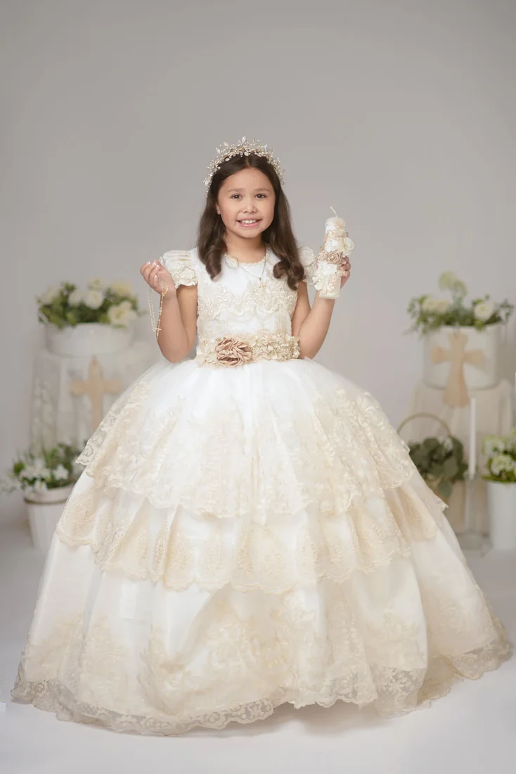 Girl seated in a white Communion dress holding a small keepsake
