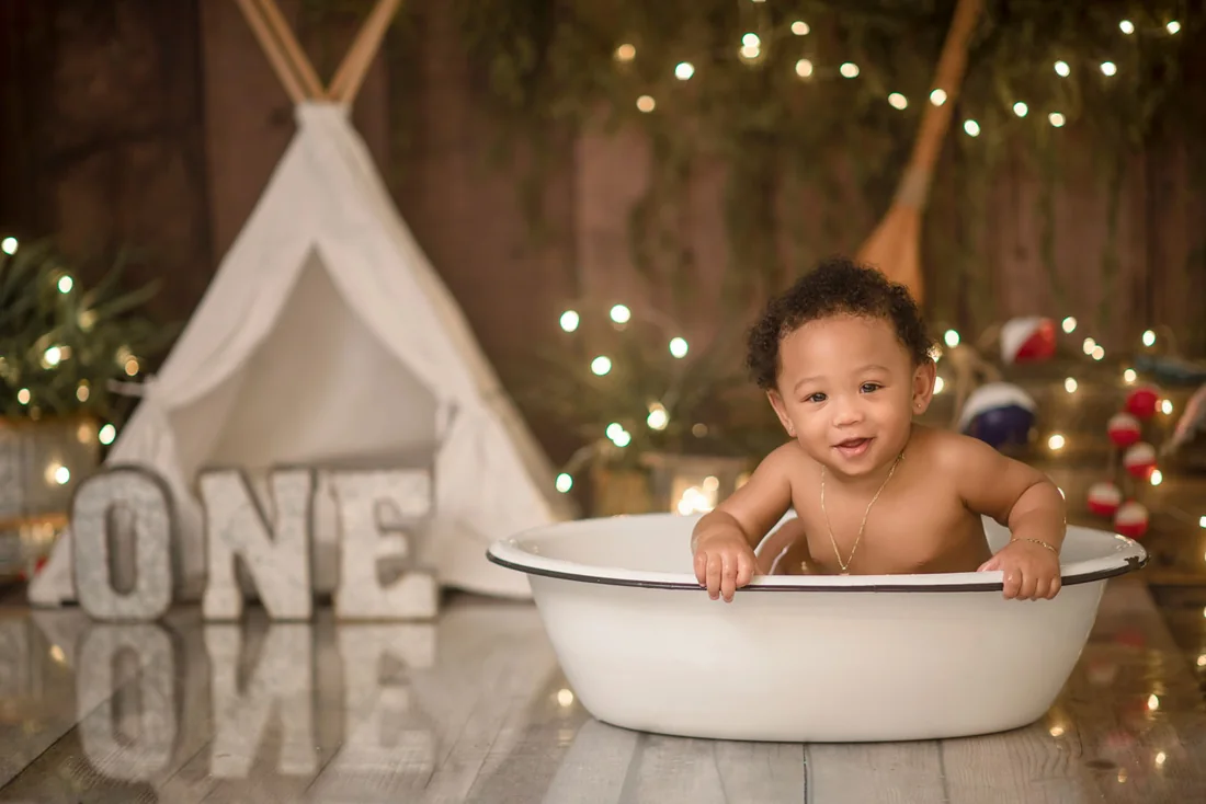 Smiling baby in a small white bath after his cake smash