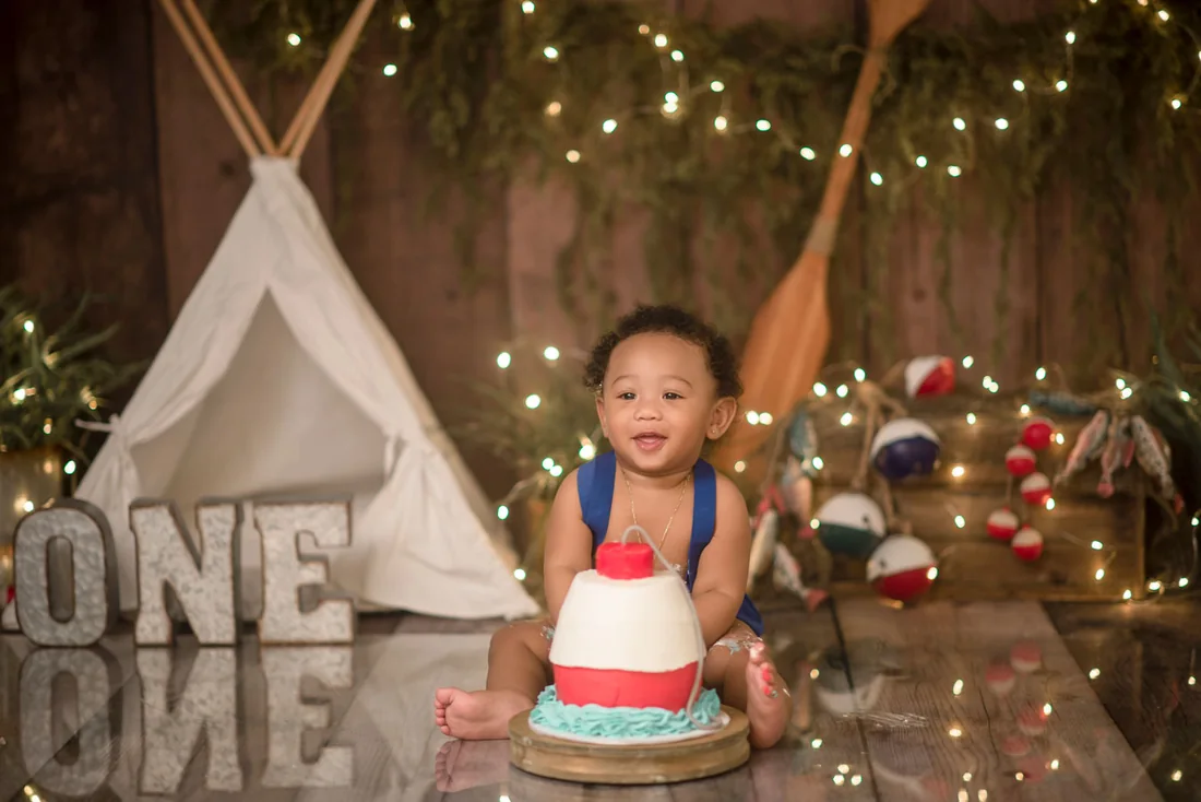 Smiling baby with frosting on his hands during his first cake smash