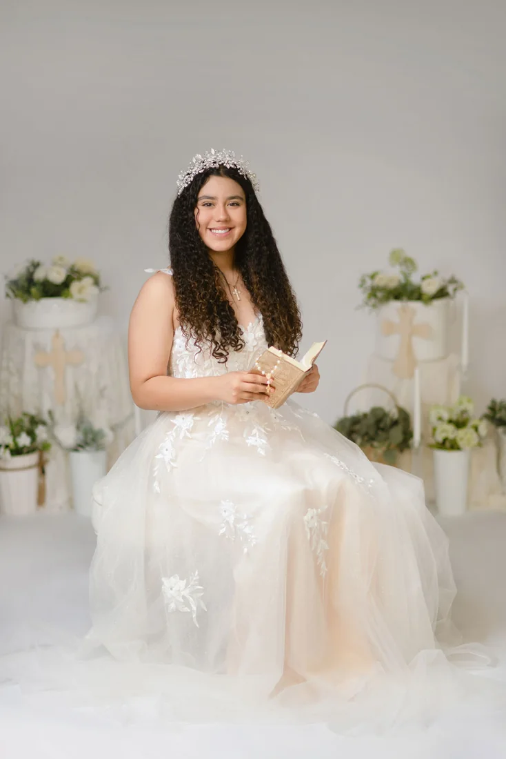 Smiling girl seated with a book during her Communion portrait session
