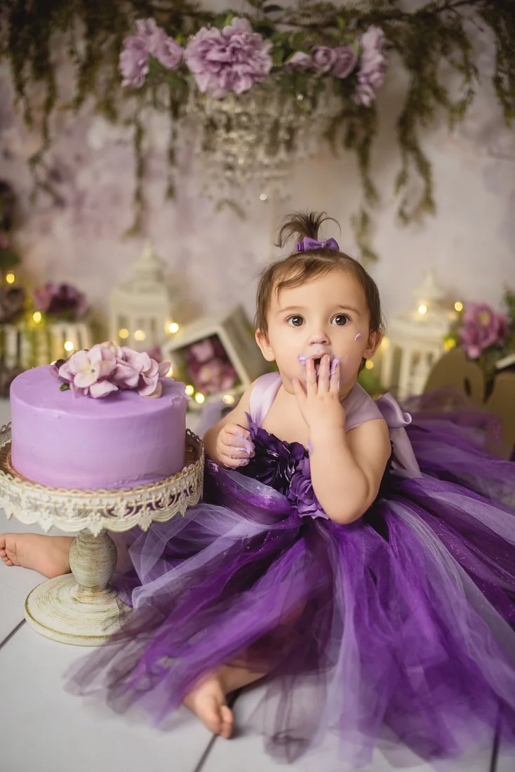 Stephanie tasting frosting beside her purple birthday cake