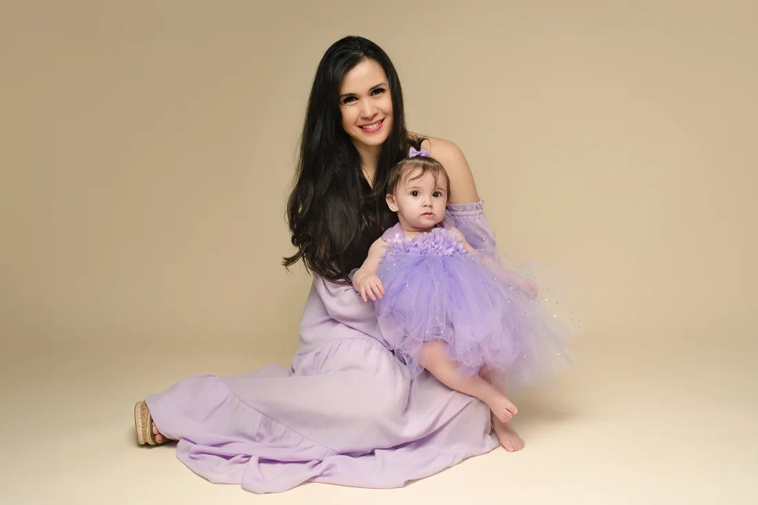 Mother seated on a warm neutral backdrop with Stephanie on her lap