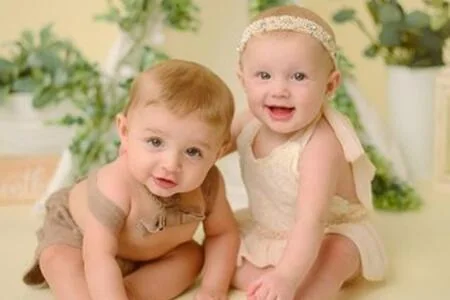Two babies sitting together in a softly styled studio portrait