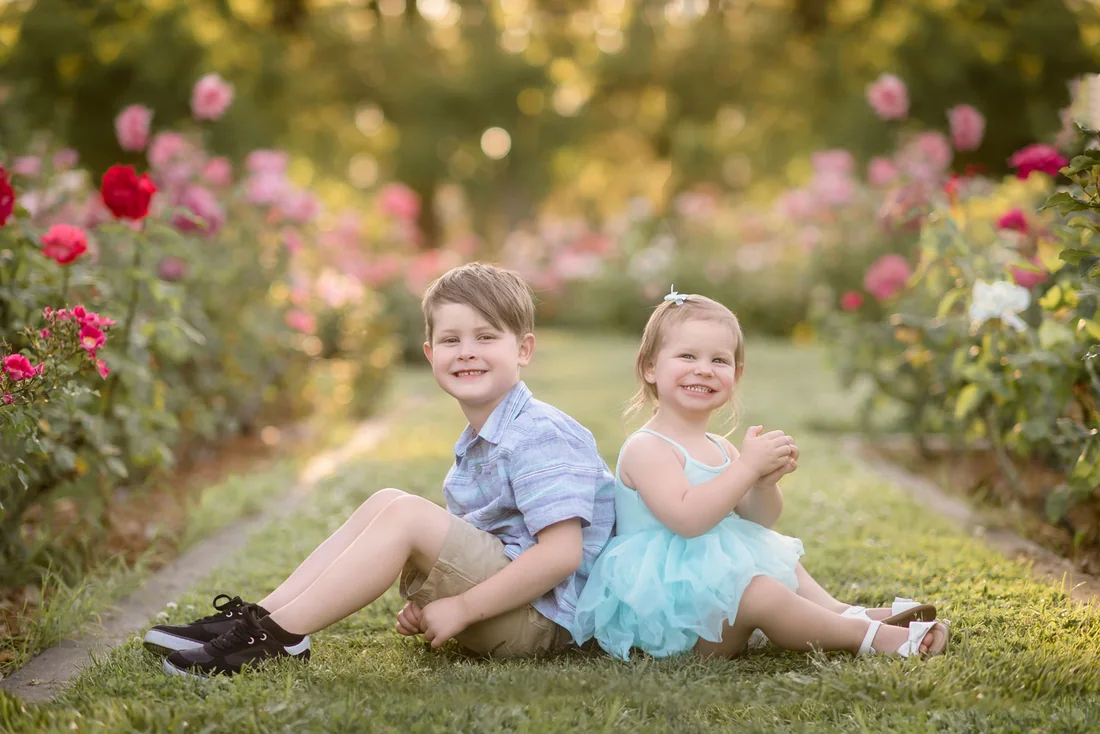 Two children sitting together on the grass in Sacramento Rose Garden