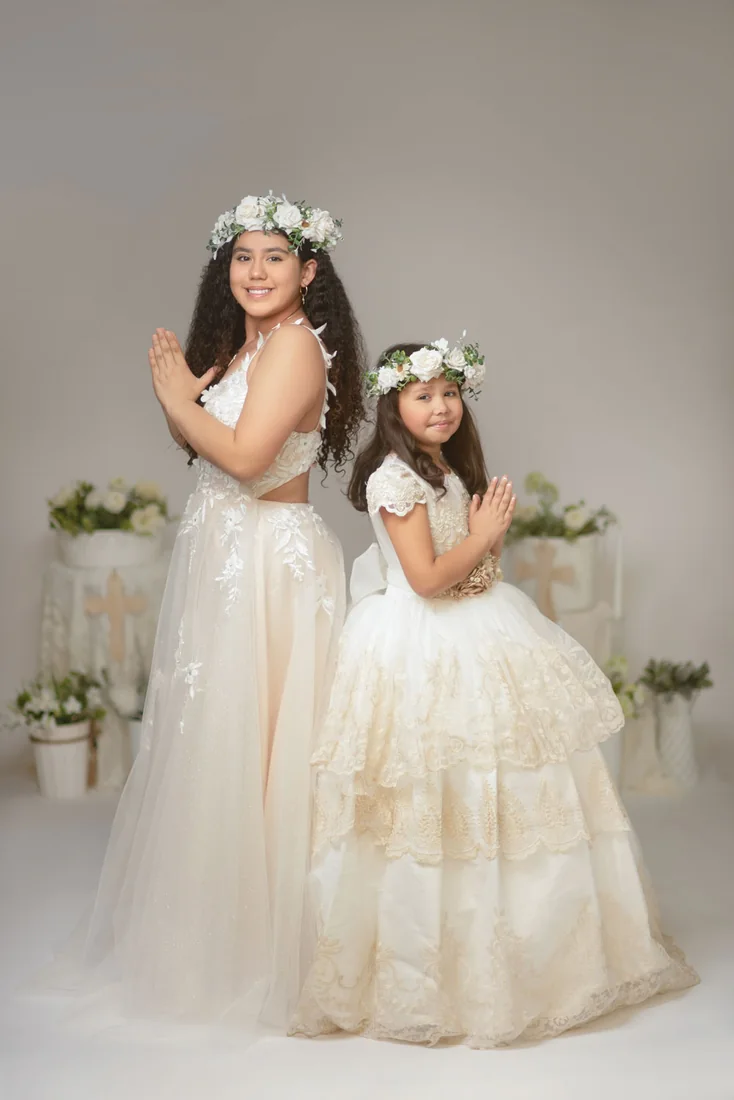 Two girls standing together in Communion dresses with floral crowns