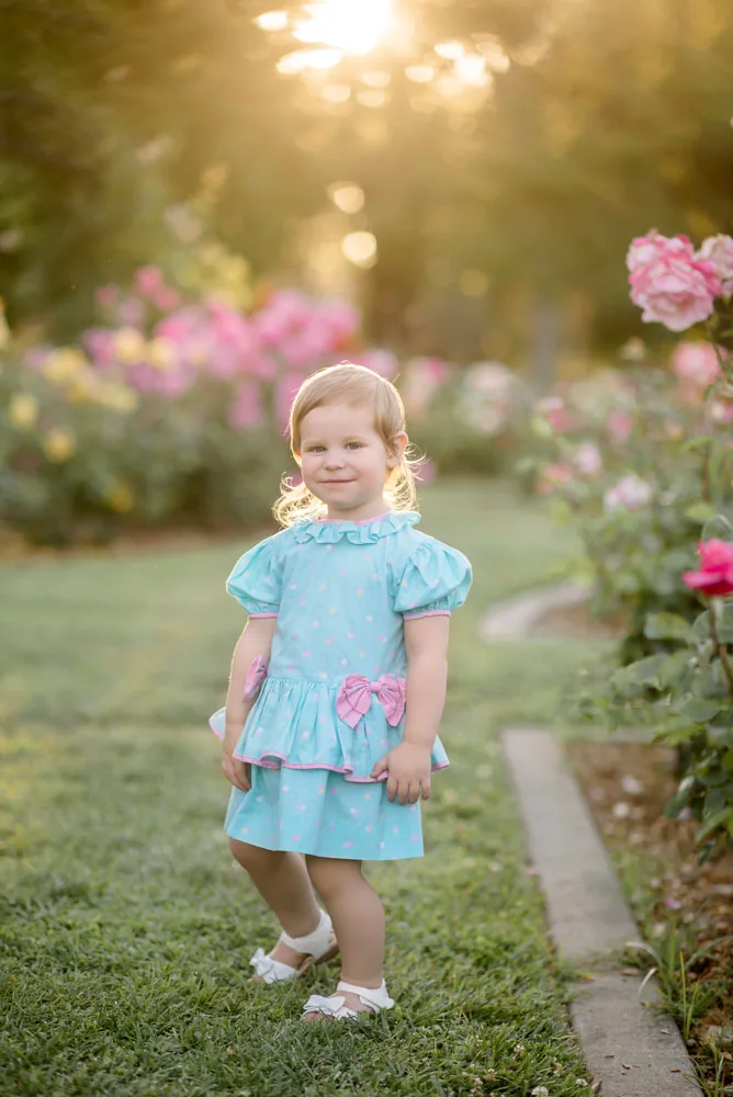 Young girl in a blue dress on a garden path in evening light